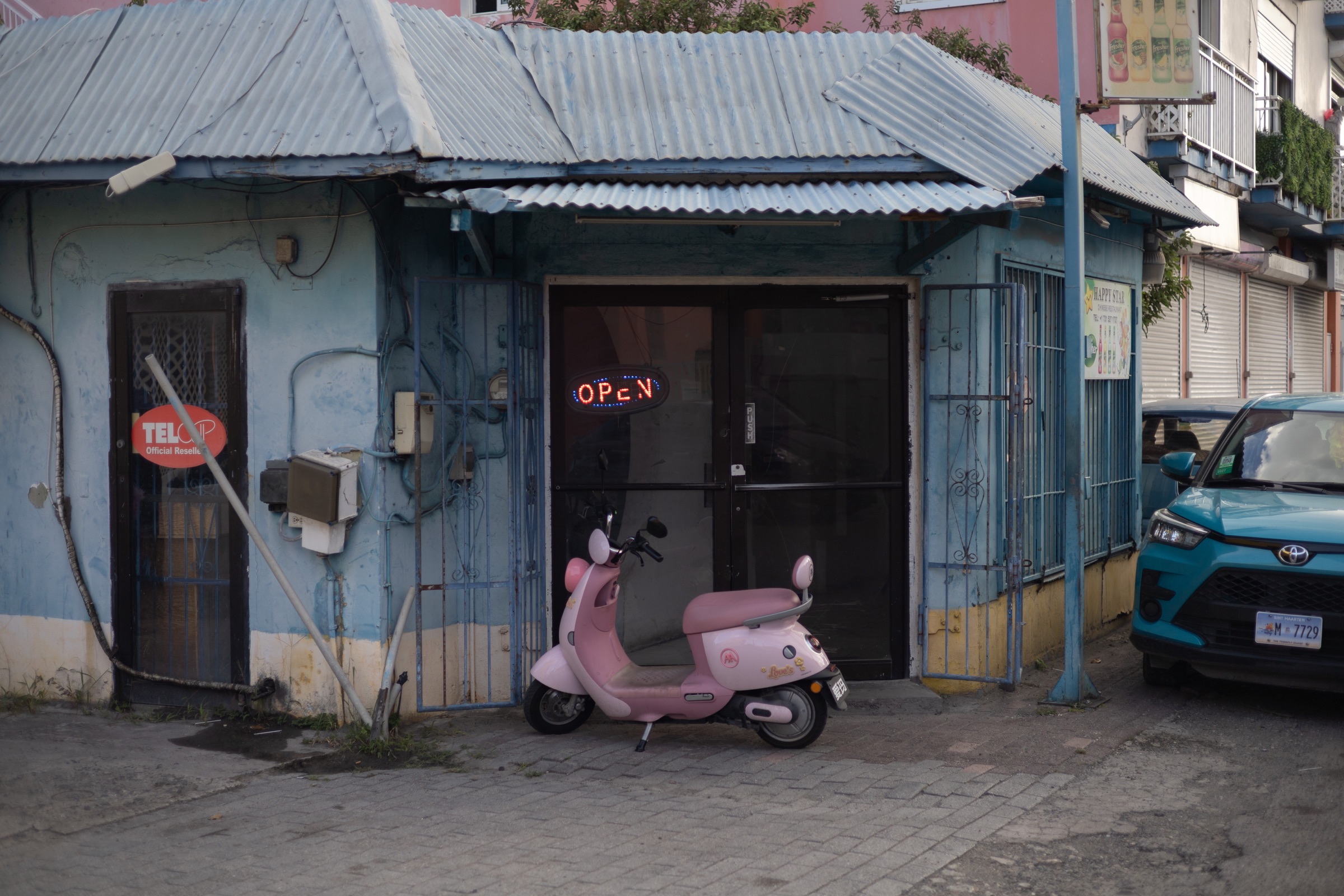 Pink scooter parked in front of a blue bar in Saint-Martin