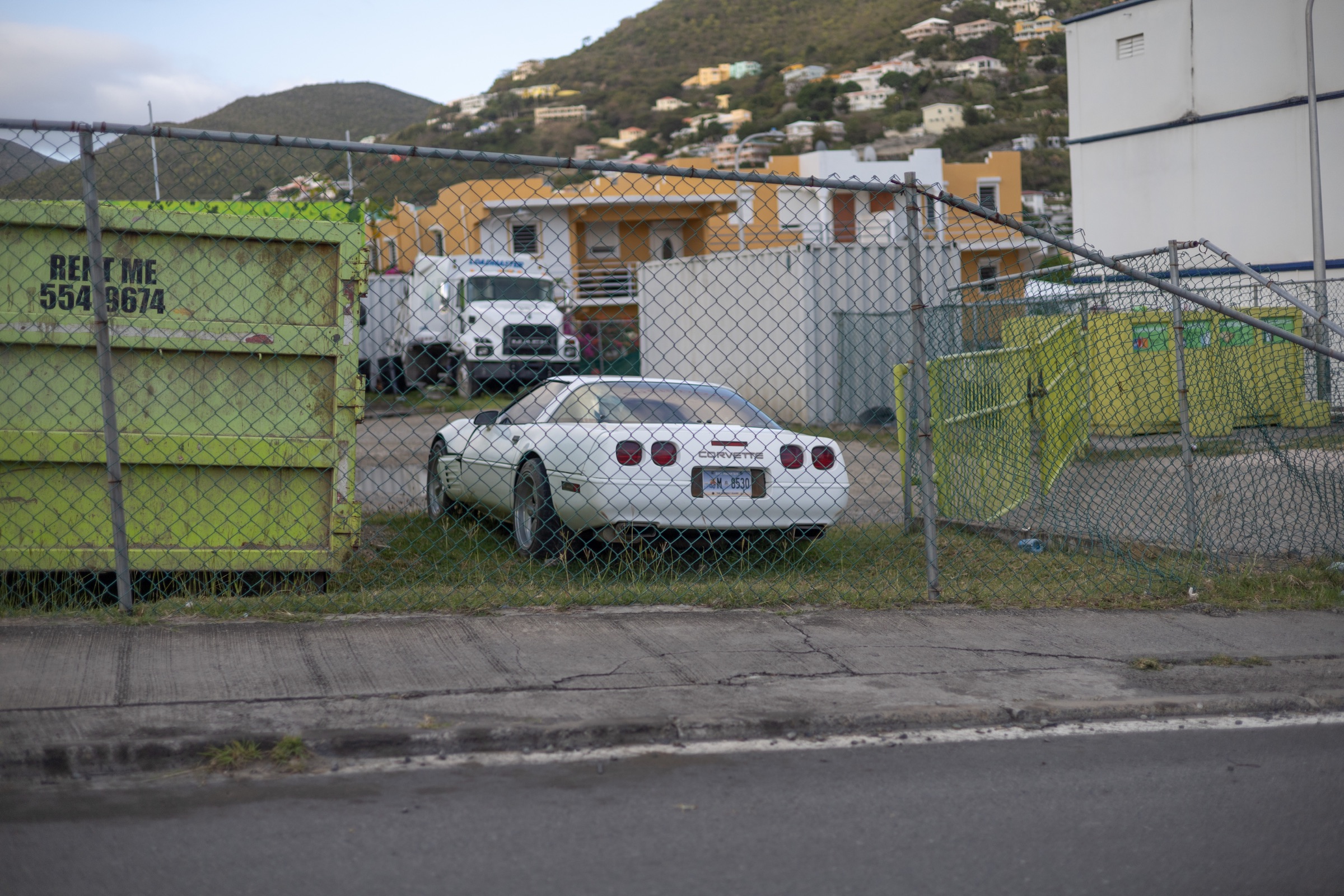 White Corvette parked behind a fence in an urban area of Saint-Martin