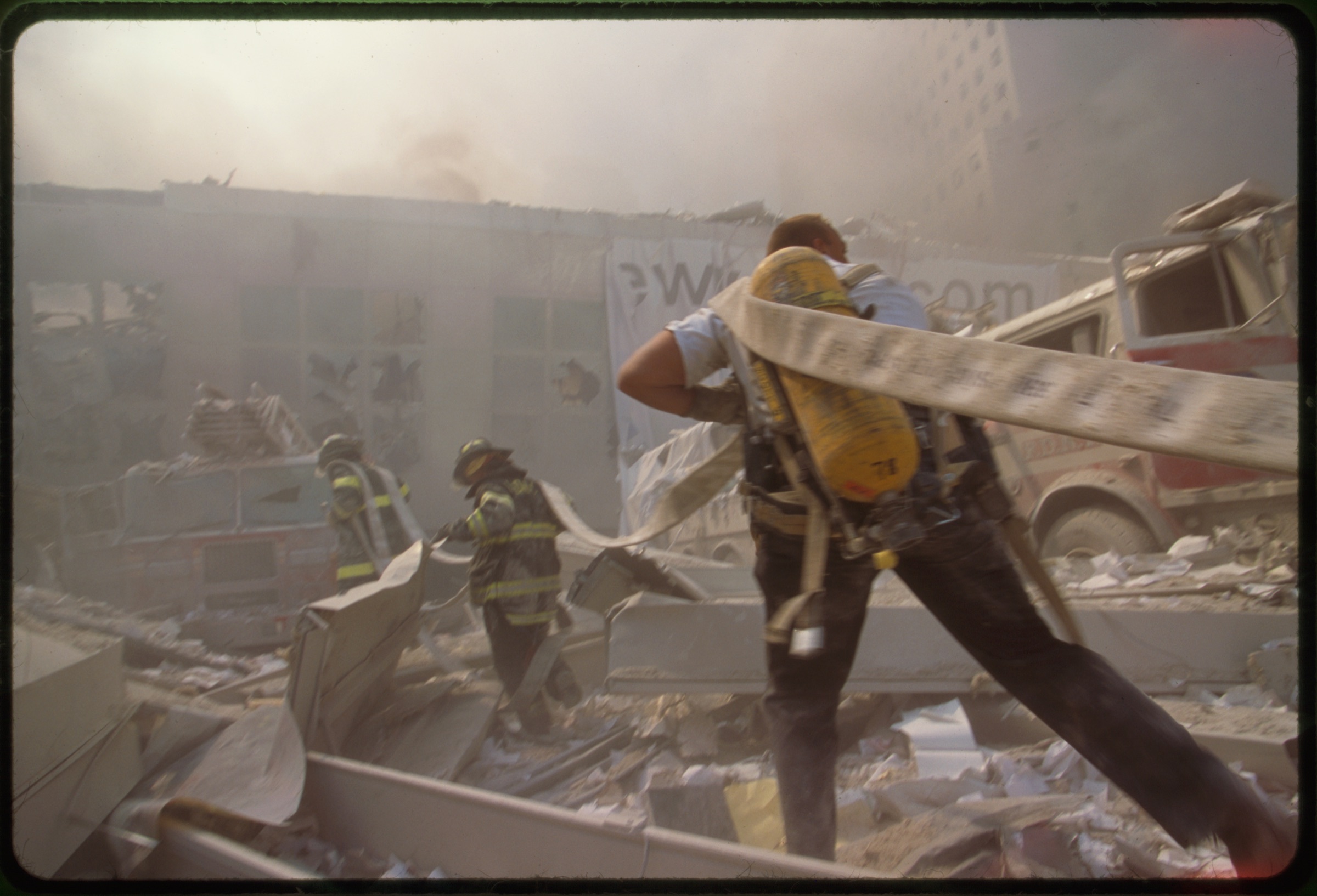 Fire fighters carrying water hose through rubble September 11th following terrorist attack on World Trade Center, New York City