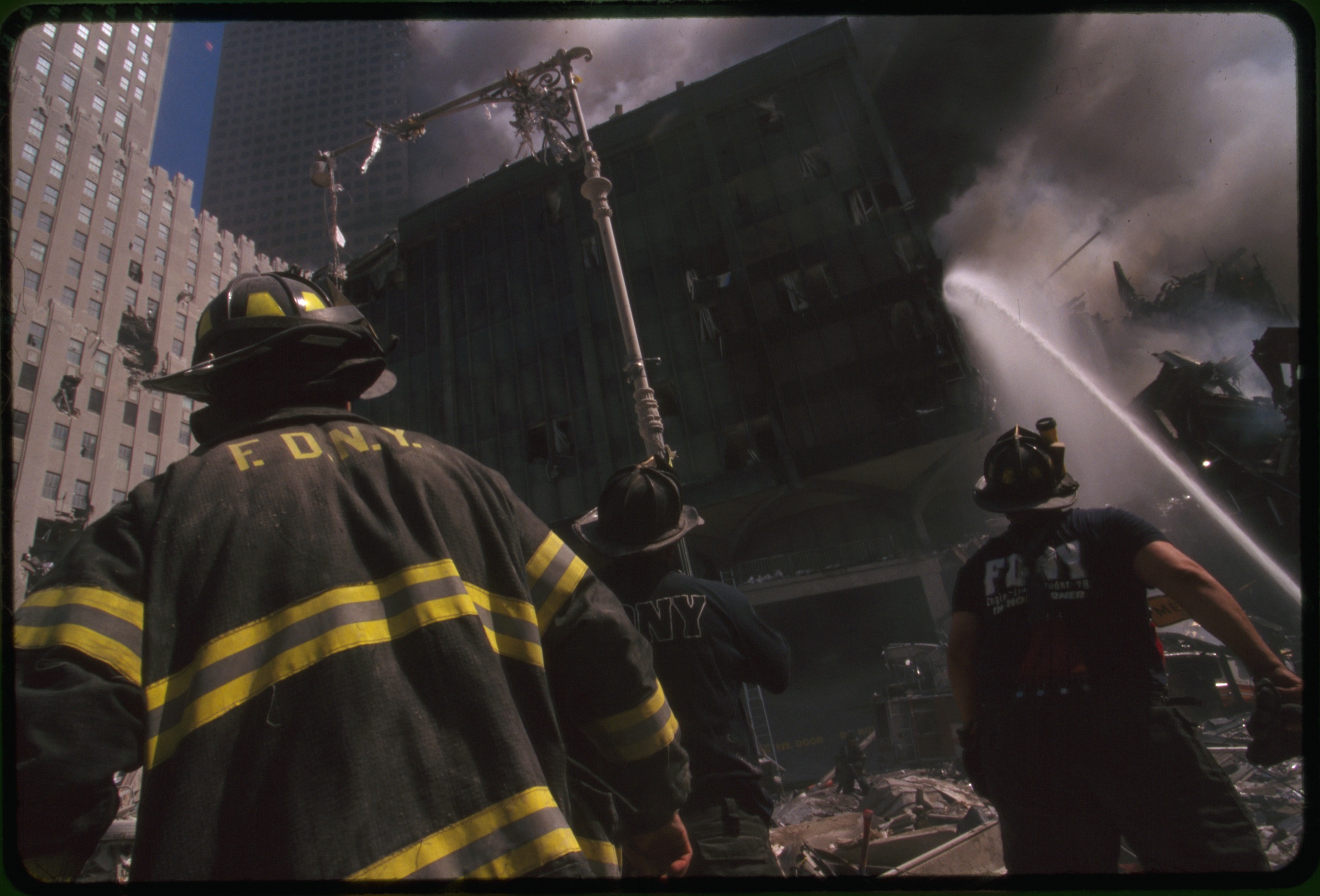 Three New York City fire fighters spraying water on smoldering ruins following the September 11th terrorist attack on World Trade Center, New York City