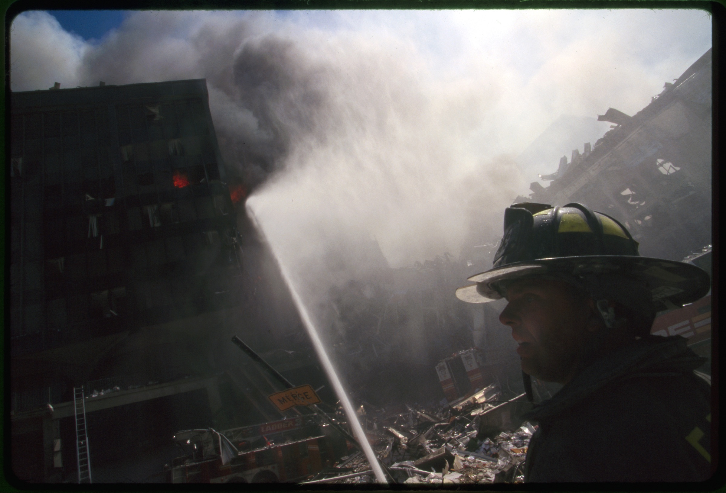 Fire fighter in front of burning building and rubble following September 11th terrorist attack on World Trade Center, New York City
